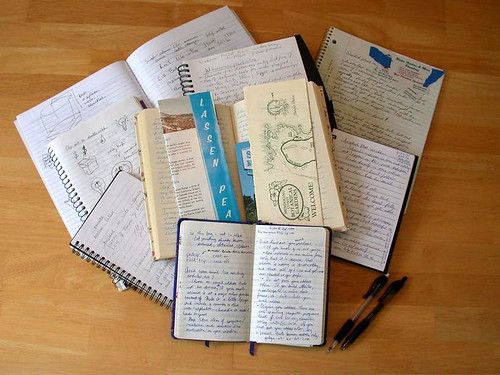 A spread of well-used notebooks and journals on a table