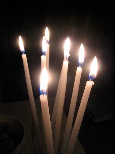 A bundle of New Beginnings tapers lit together, flames leaning gently