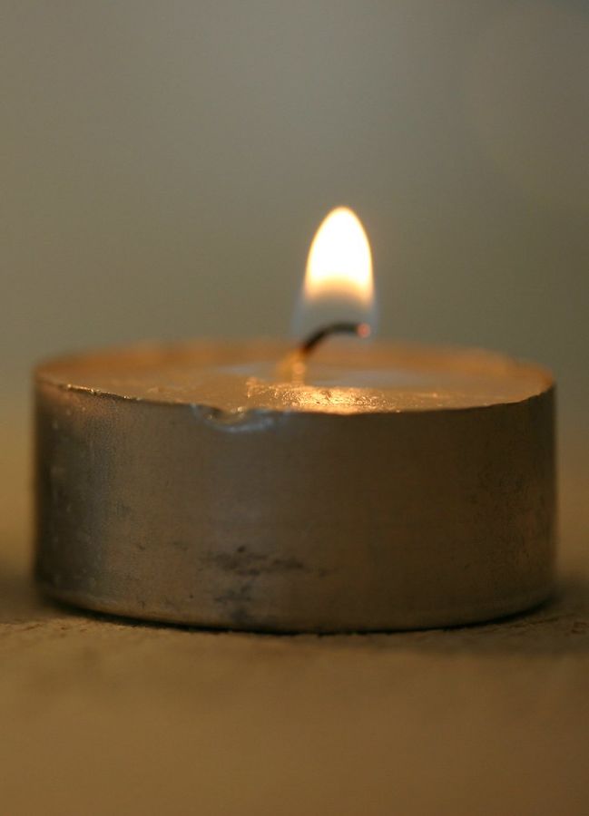 A single lit tealight glowing in close-up